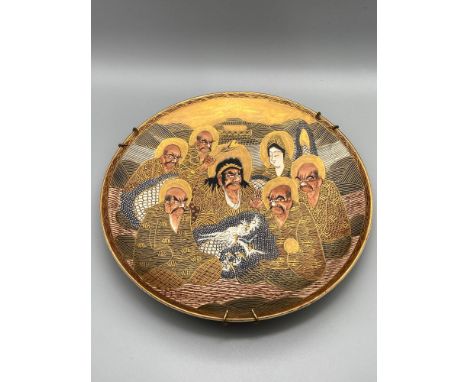 A 20th century Japanese Satsuma hand painted plate depicting various figures, dragon and temple. Signed to the back. [21cm di