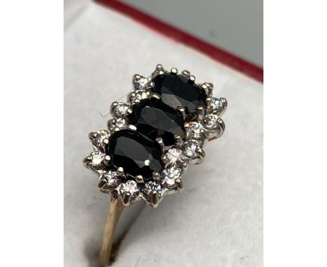 A Ladies 9ct gold ring set with three large sapphires and surrounded by clear stones. [Ring size P] [2.51Grams] 