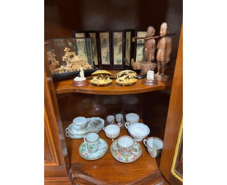 Two shelves of oriental wares to include Famille rose cups and saucers, Hand painted and lacquered screen, Cork pagoda scene 
