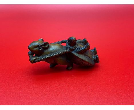 A Japanese hand carved netsuke of a mouse pulling along a turtle. Signed by the artist. Both designed with black bead eyes. 
