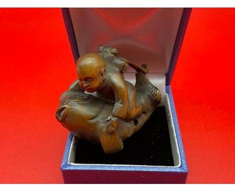 A Japanese hand carved netsuke of a young boy riding a koi carp. Koi carp is designed with black bead eyes and signed by the 