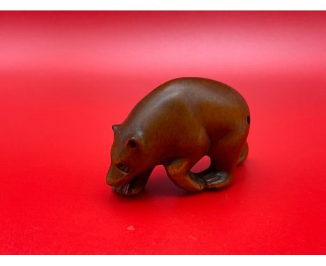 A Japanese hand carved netsuke of a Bear designed with black bead eyes and signed by the artist. 