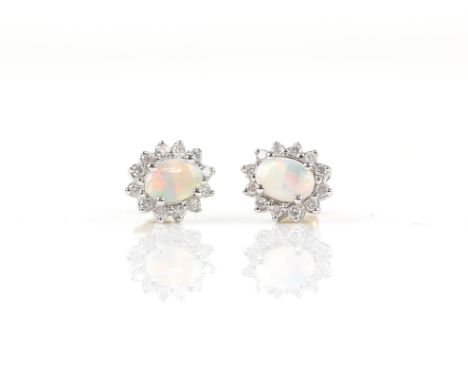 Opal and diamond stud earrings, each earring set with an oval cabochon opal with a halo of round brilliant cut diamonds, moun