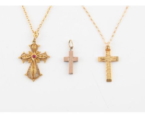 Three gold cross pendants, a filigree cross pendant set with a ruby to the centre, length 40cm, in stamped 18 ct gold, on a n