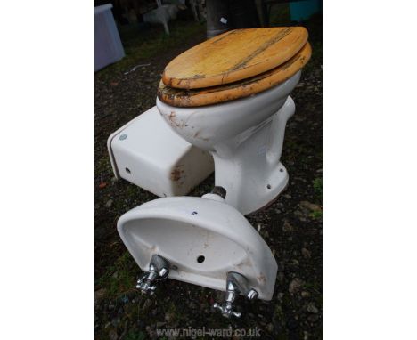 A small hand basin with taps and a low level pan and cistern.