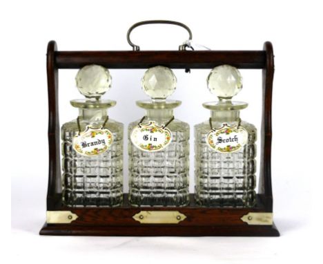 A 1920's oak mounted Tantalus with three cut glass decanters
Each with ceramic labels, with silver-plated mounts, height 31cm