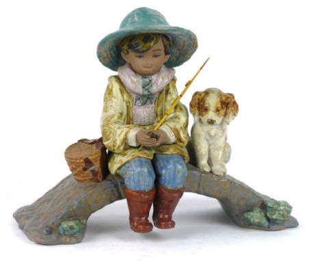 A Lladro matt finished figure group
Depicting a fisher boy seated on a bridge beside a dog, printed factory marks to base, he