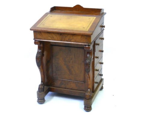 A Victorian carved walnut Davenport, the gilt tooled leather inset sloping writing surface hinged to enclose a satin maple wo