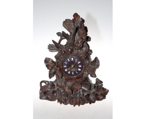 Black Forest carved mantel clock decorated with birds and foliage, 43cm high.