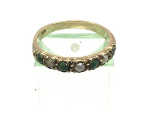 An unmarked gold ring set with pearls and green stones, possibly emeralds, approx 2.5g and approx size P-Q.