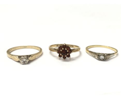 Three gold rings: two are solitaire diamond rings and one is a garnet cluster ring. One diamond ring is approximately between