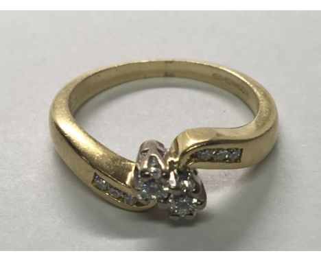 An 18carat yellow gold diamond two stone cross over ring the shank with further diamonds. Ring Size J-K