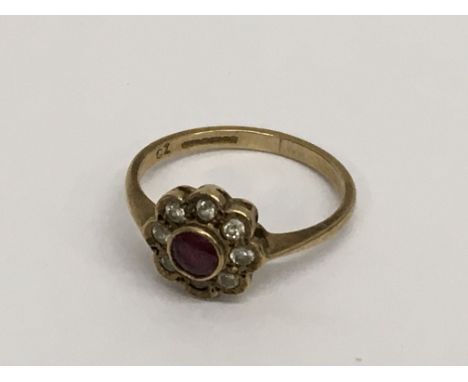 A 9ct gold ring inset with a central ruby, surrounded by small diamonds. Ring size L