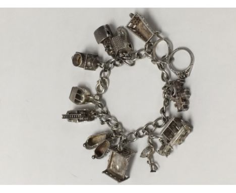 A silver charm bracelet with 12 charms attached. The charms are: a cable car, a fire engine (with lift up ladder), pair of sh