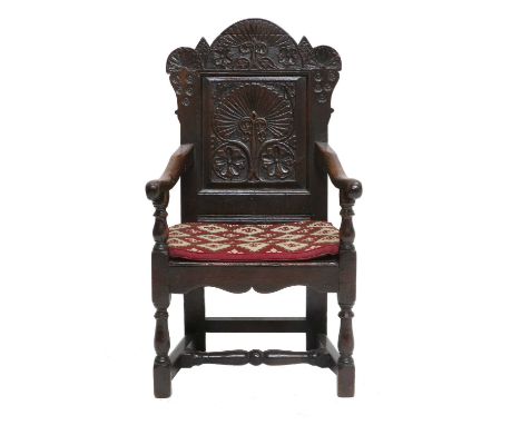 A Mid 17th Century English Joined Oak Wainscot Armchair, with single panelled back support, the carved top rail with stylised