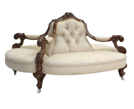 A Victorian Carved Walnut Four-Seater Conversation Sofa, circa 1870, recovered in cream and silk damask, the overstuffed back