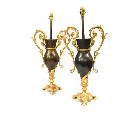 A Pair of Gilt and Patinated Metal Lamp Bases, by Bradley Hubbard, of urn form with leaf-sheathed scroll handles, on dolphin 