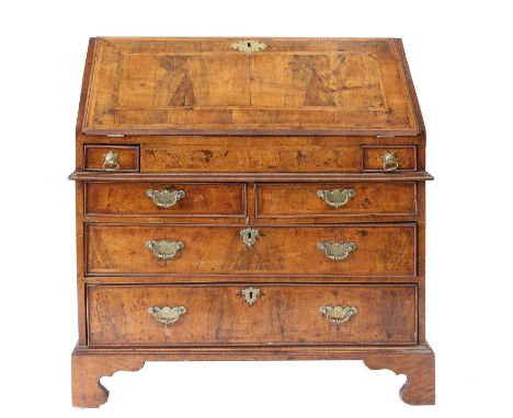 A George I Walnut Crossbanded and Featherbanded Bureau, early 18th century, the fall front enclosing an attractive fitted int