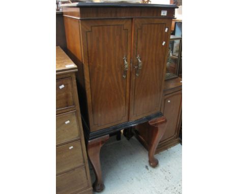 20th Century mahogany two door blind panelled cupboard with glass shelf, standing on cabriole legs and casters.(B.P. 24% incl