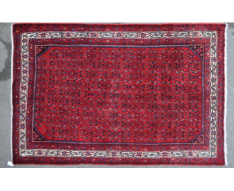 A 20th century North West Persian Hussainabad carpet floor rug. The rug having a red ground with repeating foliate motifs to 