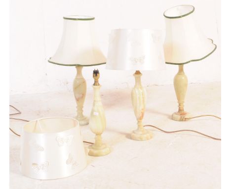 A group of four mid 20th century turned onyx table lamp lights. With light fixings to top, into a tapering body on a stepped 