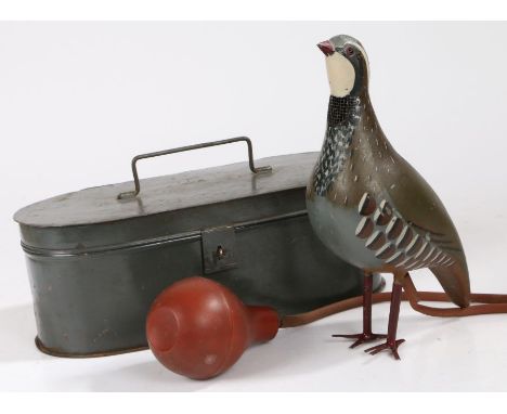 A whistling bird decoy, with a model partridge, rubber tubing and bellows to pump air into the body of the partridge, a mesh 