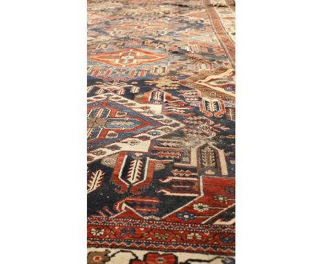 A Kurdish rug, Persia, with repeating motif in diamond lozenges together with floral guls with a carnation meandering border,