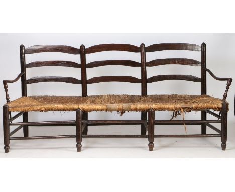 A large 18th Century French mulberry wood provincial radassier/sofa, the triple ladder back above a rush seat and sweeping an