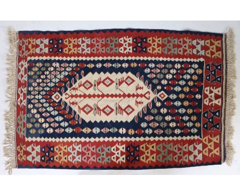 An Anatolian Slit weave Kilim, with a central motif on a cream ground surrounded by a field of diamond motifs, 176cm by 115cm