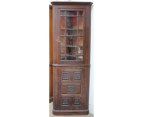 A 20th century oak standing corner cupboard, the moulded cornice above a glazed door with glazing bars, the base with a five-