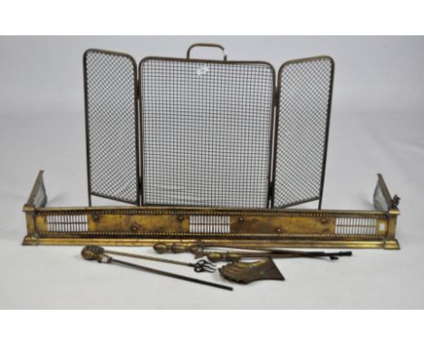 A collection of brass fireside items, including a fender, screen and irons 