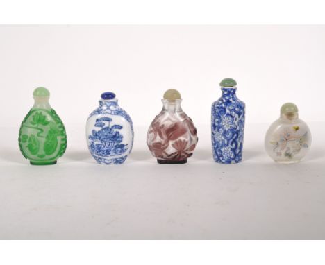 Five Oriental snuff bottles, two blue and white ceramic examples with floral decoration, and three glass bottles decorated wi