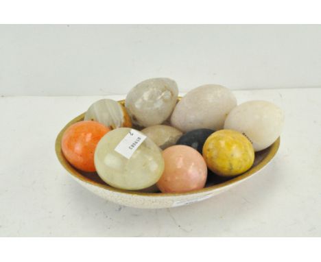 A collection of various vintage stone eggs, in a ceramic dish