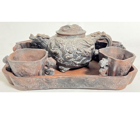 A Chinese earthenware ceramic cabaret tea set comprising a teapot with moulded dragon decoration, four twin handled cups, and