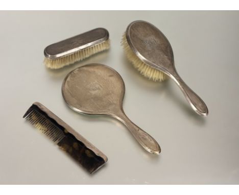 An Edwardian Chester silver backed three piece dressing table brush set to include a hand mirror, hair brush and clothes brus