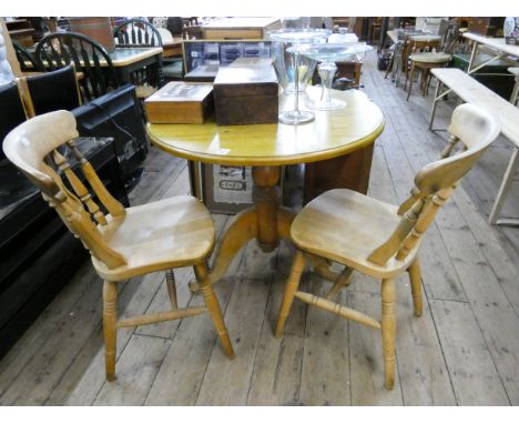 A circular light pine single pillar breakfast table and a pair of Windsor farmhouse style kitchen chairs 