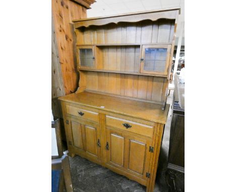 A modern light oak Welsh style dresser with a shelf back with small lead light cabinets standing on a drawer and cupboard bas