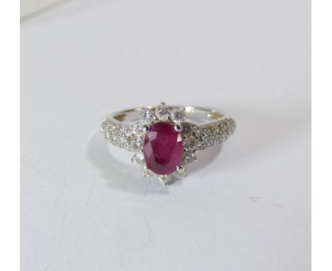 A 14ct white gold ruby and diamond cluster ring set with an oval ruby surrounded by brilliant cut diamonds with pave diamond 