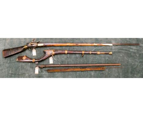 Two old Indian guns, the first a flint lock with octagonal barrel, the stock inlaid with brass, the second one is a match loc