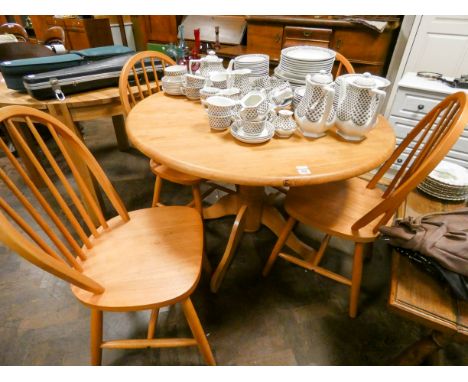 A circular light oak single pillar dining table and four matching stick back Windsor style chairs 