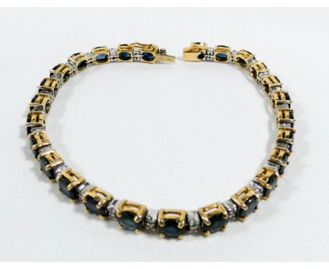 Sapphire and diamond line bracelet, claw set with 26 oval sapphires in 14 carat yellow gold. Clasp stamped 14K, 18.5 cms long