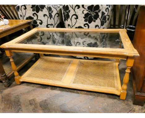 A modern light oak coffee table with inset glass top and cane under tier 45" x 25" 