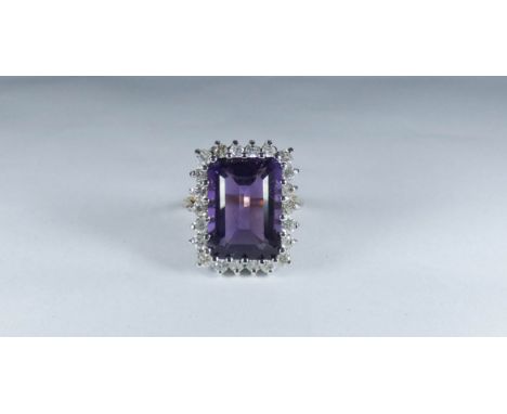Large and impressive amethyst and diamond cluster ring set with a large trap cut amethyst surrounded by brilliant cut diamond