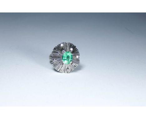 Unusual emerald and diamond cocktail ring set with a large oval emerald to the centre within a retro style setting decorated 