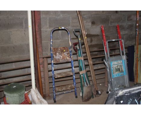 Two bundles of long handled gardening tools and a set of steps