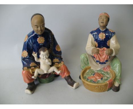 A pair of Chinese stoneware seated figures, each part glazed, one depicting a man washing clothes in a tub the other of a man