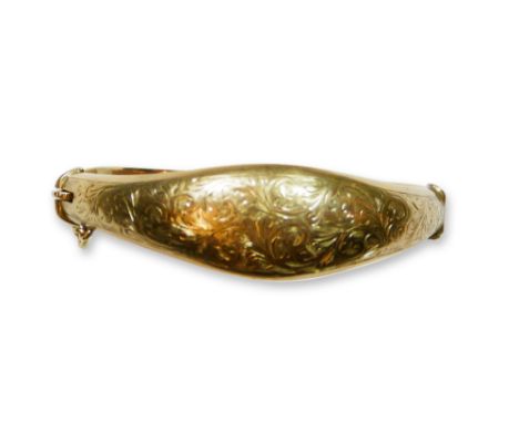 A 9ct gold hinged bangle, Birmingham 1954, the shaped front with engraved floral decoration, weight 15.5 grams. 