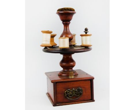 A Victorian walnut sewing companion, the central baluster turned stem with pin cushion top, central revolving bobbin carousel