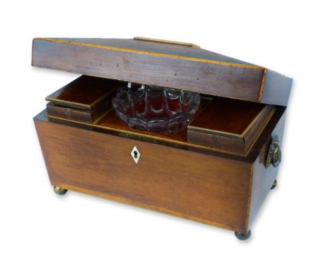 A 19th century mahogany tea caddy, of sarcophagus shaped form with two lion mask handles and four ball feet, the hinged lid o