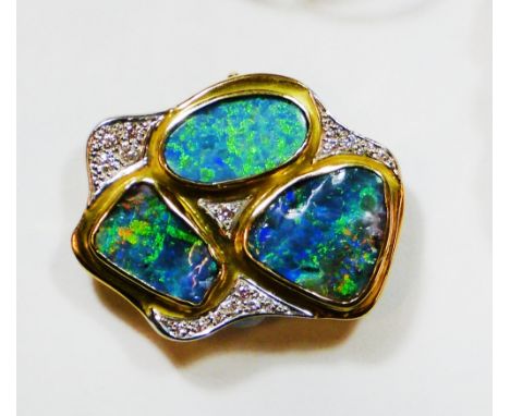 An 18ct gold black opal doublet and diamond brooch, the collet set rough polished stones bordered by brilliants, weight 16 gr